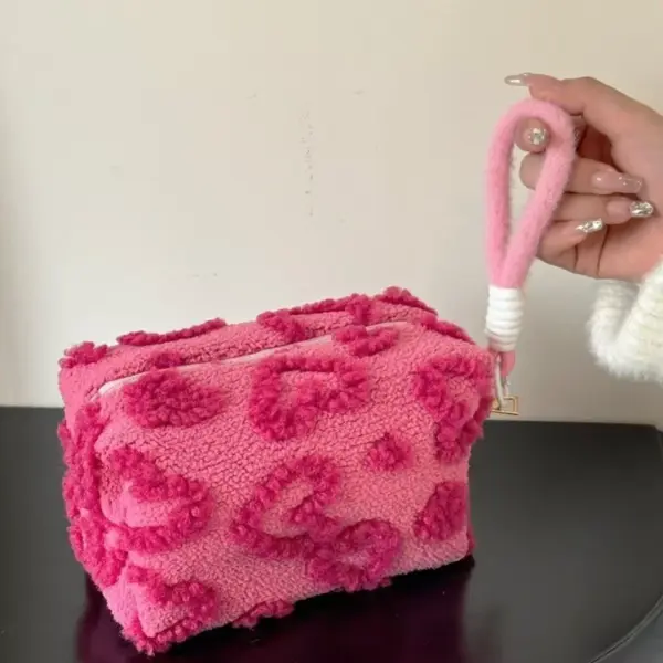 Gros plan sur la matière peluche moelleuse et le motif cœur décoratif de la trousse